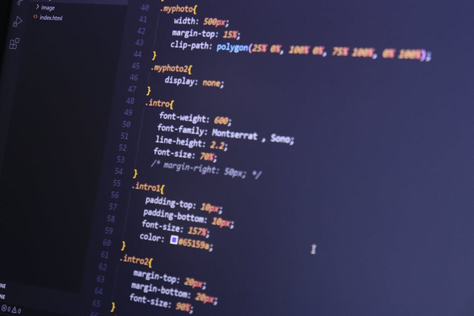 The image displays a close-up of a computer screen with lines of CSS code in various colors, including yellow, pink, blue, and orange, set against a dark background. The code snippets include specific